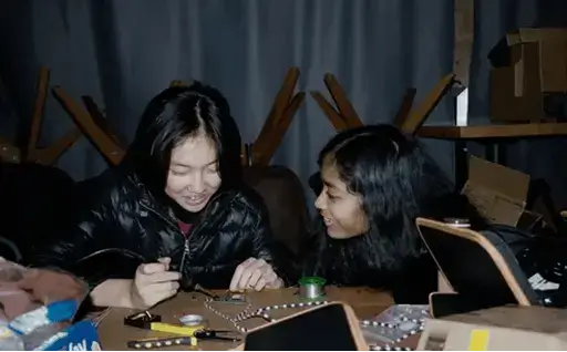 Two teenagers building electronics at a Hack Club event